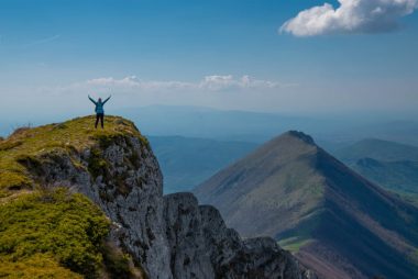 A person celebrating victory atop a mountain peak in Serbia with breathtaking views.